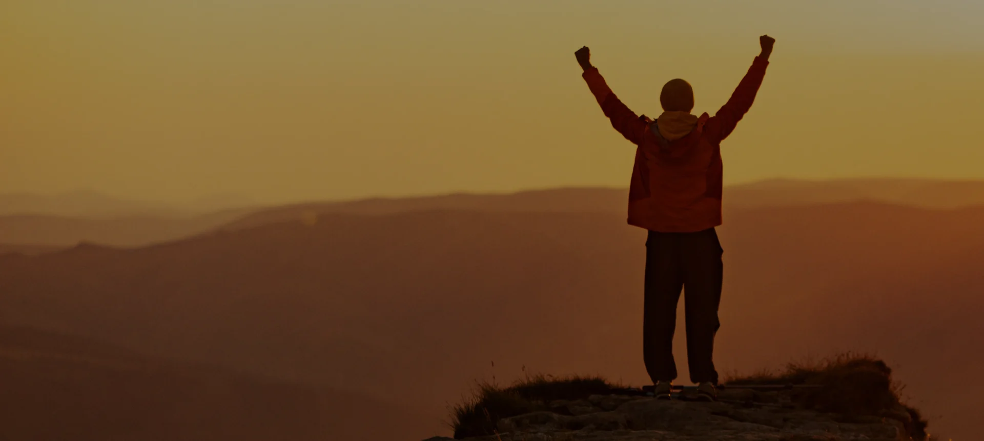 Victory pose on mountain peak at dusk